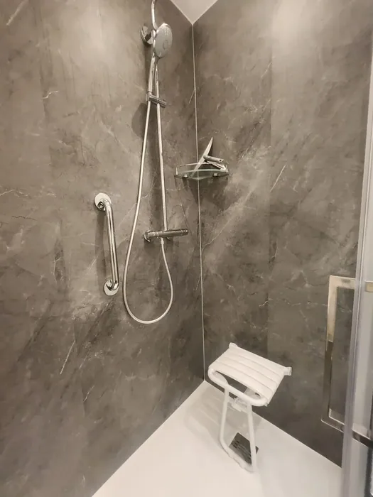 Douche met grijze marmerlook wandpanelen, opklapbaar douchezitje, steunbeugel en thermostaatkraan met glijstang