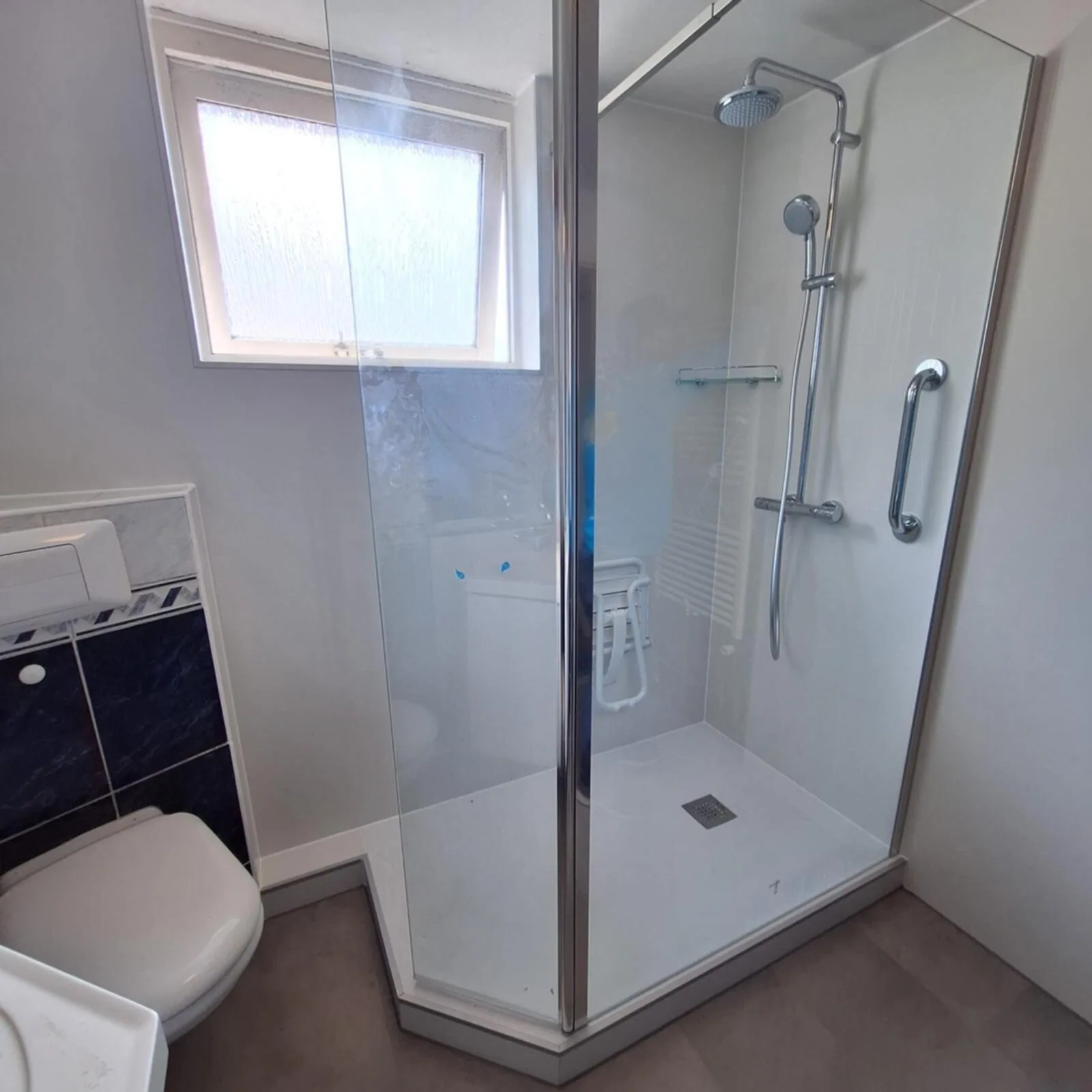 Aangepaste badkamer met drempelloze douche, steunbeugel, opklapbaar douchezitje en hangtoilet