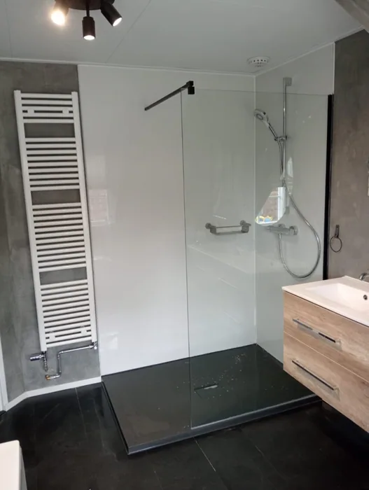 Inloopdouche met witte wandpanelen, zwarte douchevloer, glazen wand en houten wastafelmeubel