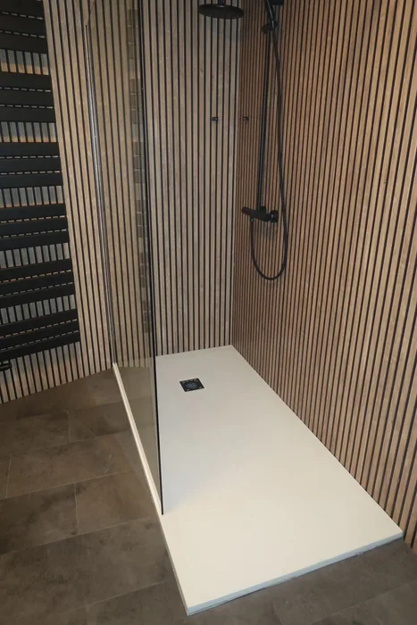 Inloopdouche met witte douchebak, zwarte regendouche en wand met houten lamellenpanelen
