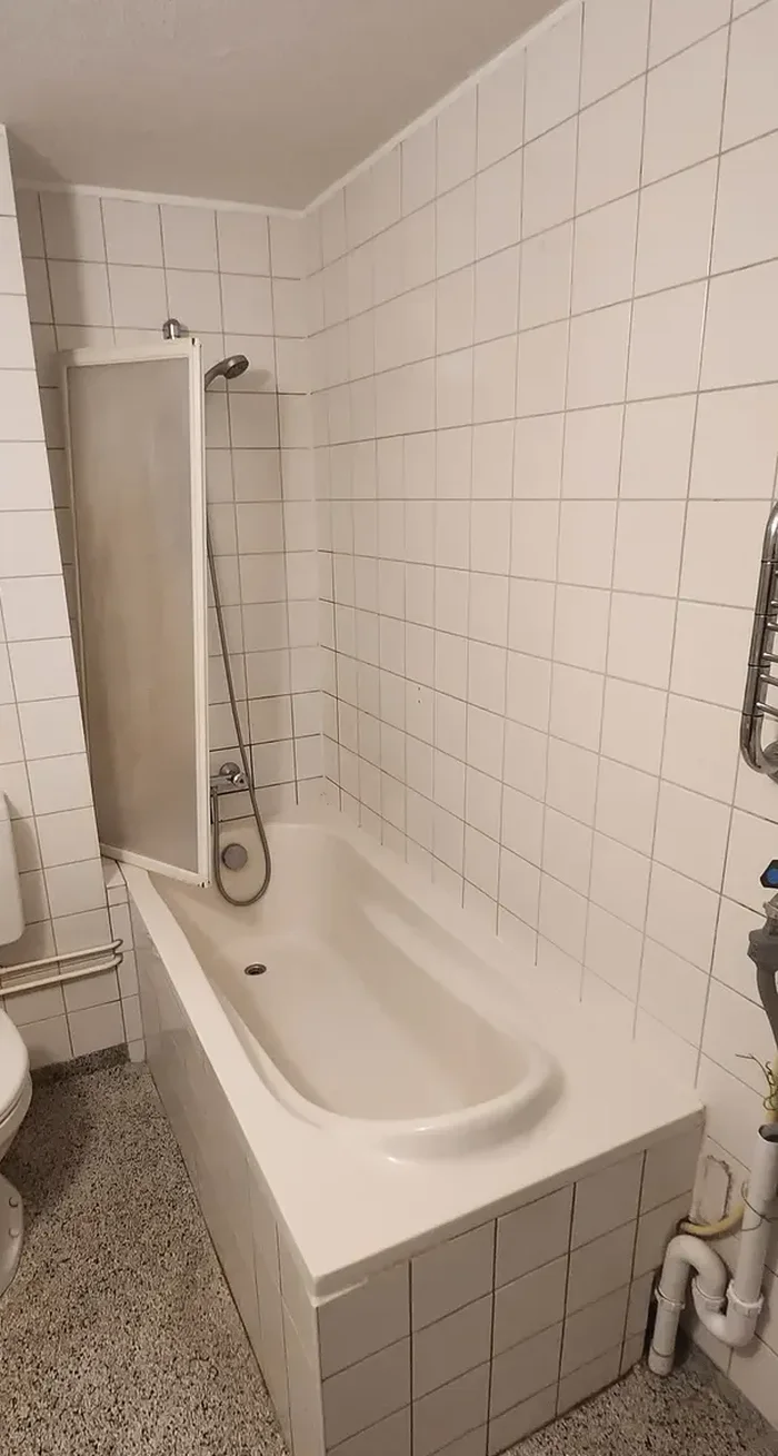 Voor: Oude badkamer met ligbad met badscherm, staand toilet met reservoir, witte tegels en spikkelvloer